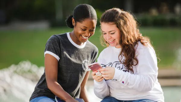 Two UCF students are sharing something on their phones.