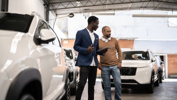 Salesman showing a car to a customer in a car dealership.